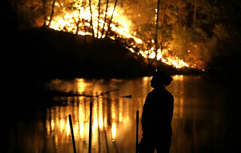 A firefighter stands near a wildfire in Middletown, Calif., on Sunday, Sept. 13, 2015. Two of California’s fastest-burning wildfires in decades overtook several Northern California towns, killing at least one person and destroying hundreds of homes and businesses. CREDIT: AP PHOTO/ELAINE THOMPSON