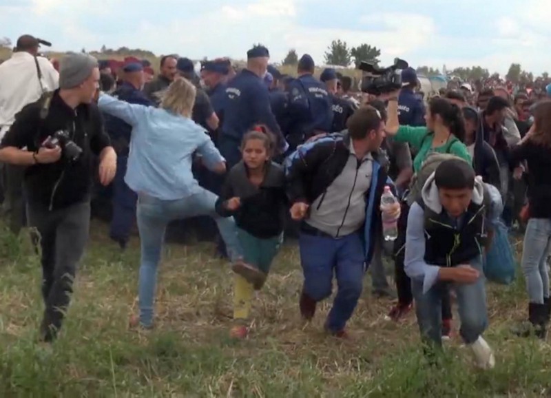 In this image taken from TV a Hungarian camerawoman, center left in blue, kicks out at a young migrant who had just crossed the border from Serbia near Roszke Hungary Tuesday Sept. 8, 2015. CREDIT: INDEX.HU. VIA AP