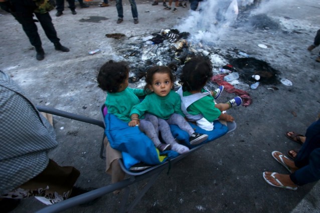 A migrant pushes a wheelbarrow with children at the “Horgos 2” border crossing into the Hungary, near Horgos, Serbia, Wednesday, Sept. 16, 2015. CREDIT: AP Photo/Darko Vojinovic