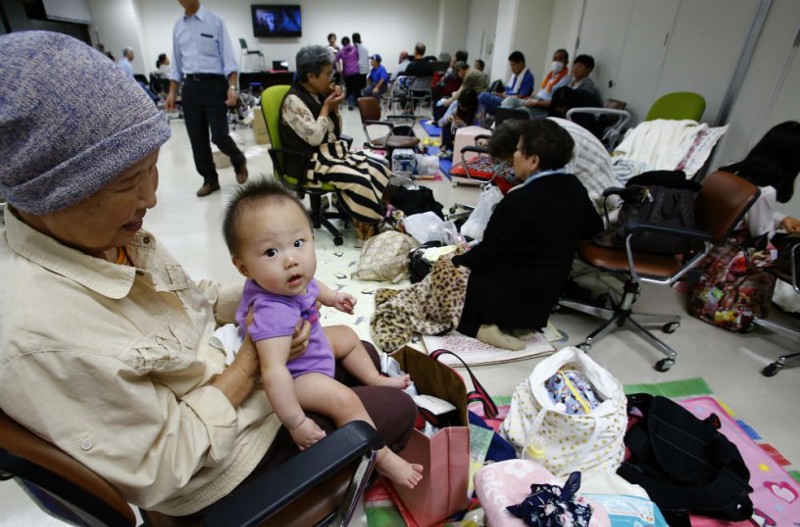 A woman holds her grandchild as evacuees of flood-stricken Joso city take refuge in a City Hall in Joso, Ibaraki prefecture, northeast of Tokyo, Thursday, Sept. 10, 2015. CREDIT: AP Photo/Shizuo Kambayashi