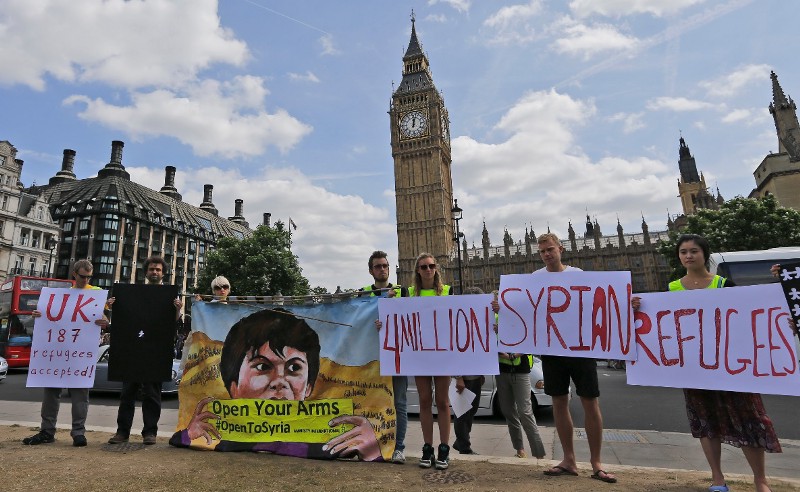 Protestors hold banners during an Amnesty International protest in Parliament Square to urge the British government to do more to help Syrian refugees in London. CREDIT: AP PHOTO/FRANK AUGSTEIN