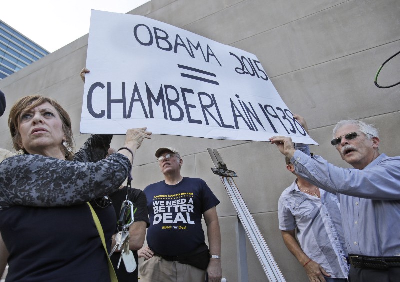 Lesley Kaplan, left, and her husband, Rabbi Robert Kaplan, of North Miami Beach, Fla., right, hold up a sign comparing President Obama with British Prime Minister Neville Chamberlain. CREDIT: AP PHOTO/WILFREDO LEE