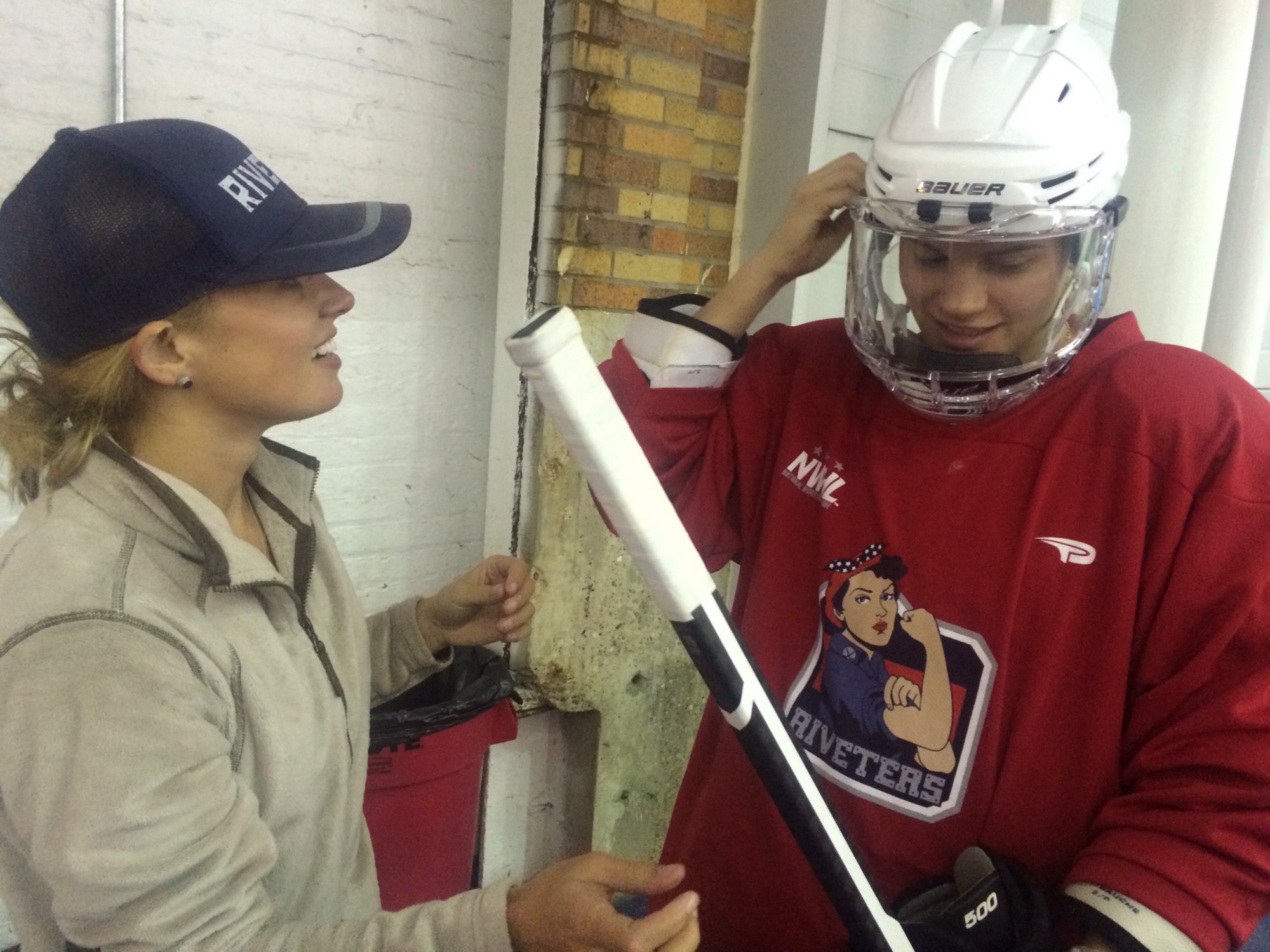 NWHL Commissioner Dani Rylan helps with a helmet fitting. CREDIT: LINDSAY GIBBS