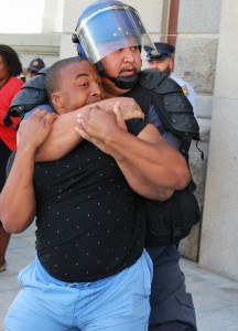 A protesting university student clashes with a riot policeman outside Parliament in Cape Town, South Africa, Wednesday Oct. 21, 2015. CREDIT: AP Photo/Nardus Engelbrecht