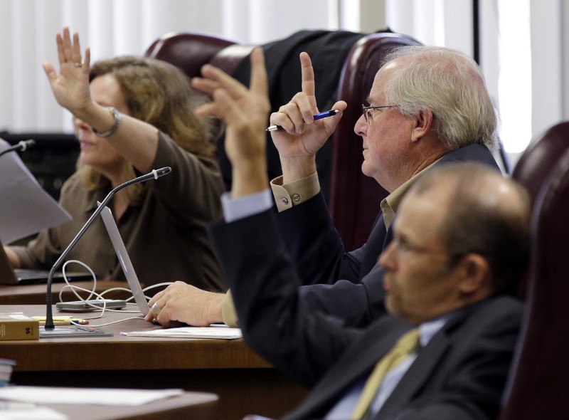 State Board of Education board members, from left, Donna Bahorich, David Bradley, and Thomas Ratliff, raise their hands to ask questions. CREDIT: ERIC GAY, AP