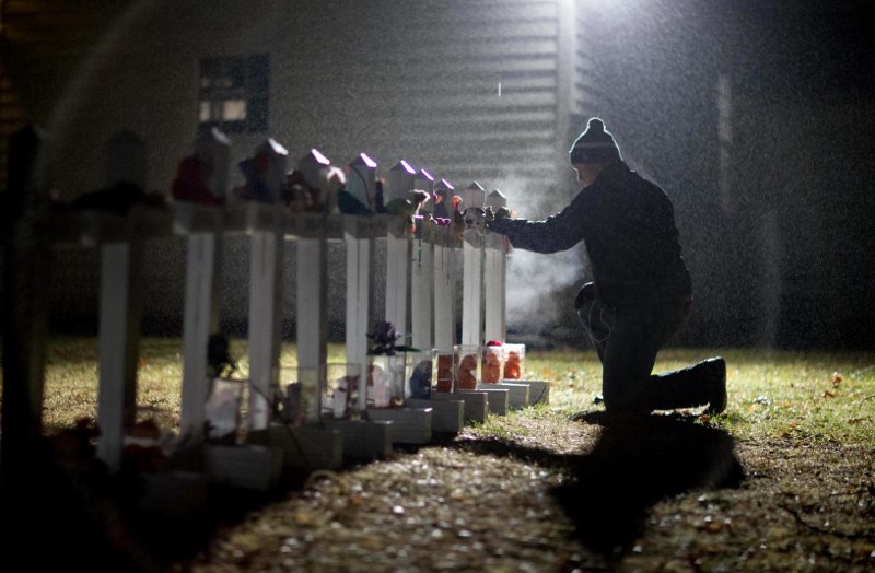Frank Kulick, adjusts a display of wooden crosses, and a Jewish Star of David, representing the victims of the Sandy Hook Elementary School shooting, on his front lawn, Monday, Dec. 17, 2012, in Newtown, Conn. CREDIT: AP Photo/David Goldman