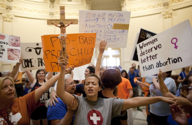 Religion is typically associated with efforts to restrict abortion rights. In this photo, anti-abortion rights supporter Katherine Aguilar holds a crucifix and prays in the State Capitol rotunda in Austin, Texas. CREDIT: AP Photo/Tamir Kalifa, File