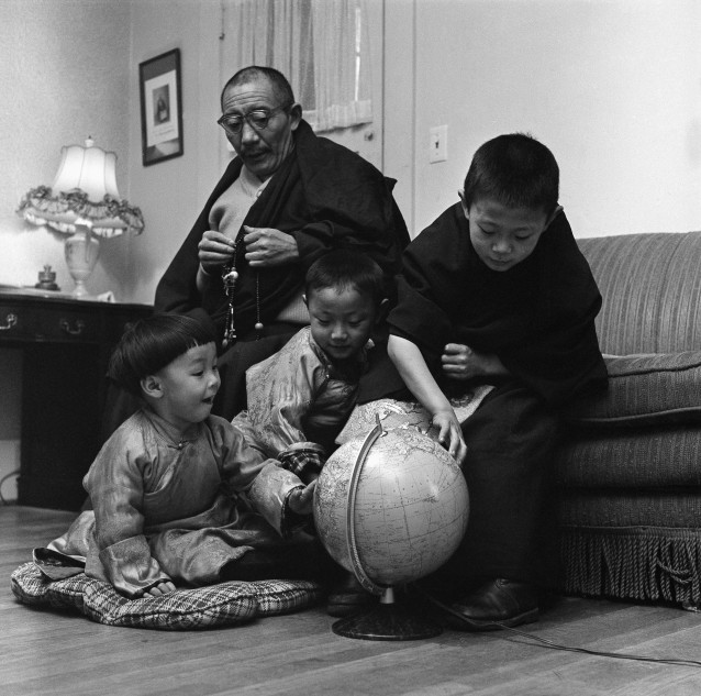 Lama Dezhung Labrang fingers a Buddhist rosary while the three sons of Lama Jigdal Sakyapa try to find Tibet and Seattle, Wash., on a globe, Jan. 9, 1961. The boys are, from left, Lotroy, 2, Kunga, 4, and Zayang Dorje, 6, who is heir to the throne of the Sakyanas. (AP Photo) CREDIT: AP Photo