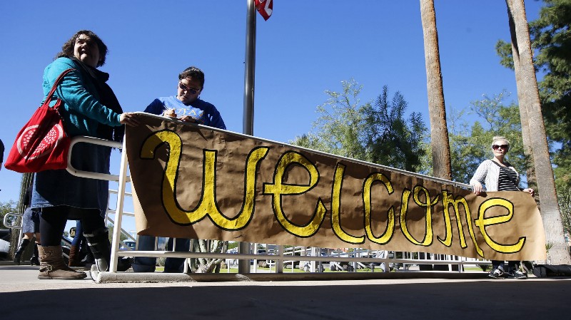 Supporters place a sign welcoming Syrian refugees is placed at the entrance to the office of the Arizona governor during a rally at the Arizona Capitol Tuesday, Nov. 17, 2015, in Phoenix. CREDIT: AP PHOTO/ROSS D. FRANKLIN
