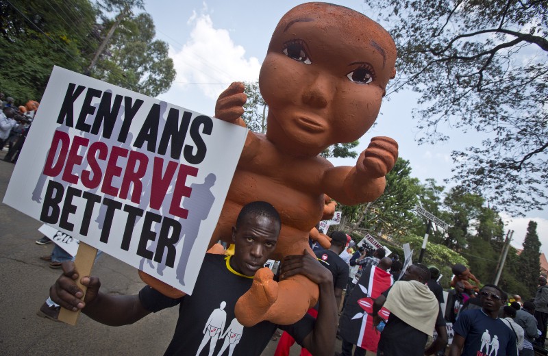 Protesters carry giant mock babies to represent what they claimed was the “childish” apathy of the Kenyan people and the need for the country to “grow up”, before police fired teargas to disperse the demonstration in downtown Nairobi, Kenya Thursday, Feb. 13, 2014. CREDIT: AP PHOTO/BEN CURTIS