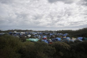 In this photo from before the fire, Hundreds of tents stand between bushes in France’s biggest refugee camp near Calais. CREDIT: AP Photo/Markus Schreiber