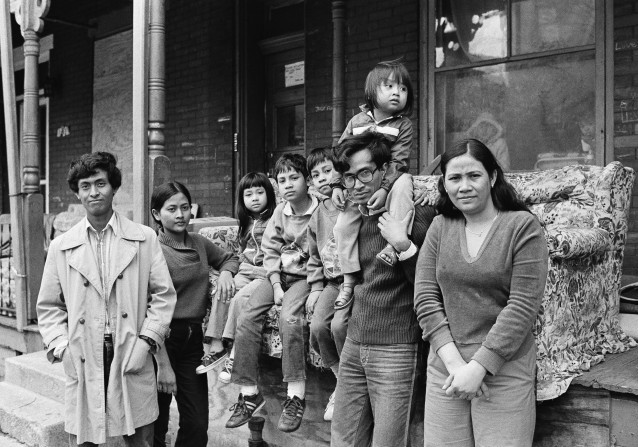 Nou Moeur, a Cambodian refugee, carries his daughter on this shoulders as his wife Orrin, right, and his children, and brother Nou Samean, sister Nou Yat, rear, are shown outside their row home in Harrisburg, Penn., March 17, 1983. The extended family was forced to move from the Flatbush area of Brooklyn, N.Y., after being subjected to muggings and other acts of violence. Several other Cambodian refugee families joined them. (AP Photo/Paul Vathis) CREDIT: AP Photo/Paul Vathis