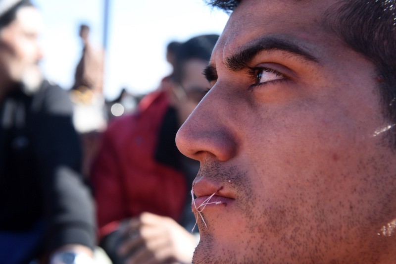 A migrant sits in no-man’s land with his mouth sewn shut during a protest near the village of Idomeni at the Greek-Macedonian border, on Monday, Nov. 23, 2015. Several European countries, including EU members Slovenia and Croatia and non-members Serbia and Macedonia, have declared they will only allow “war-zone refugees” from Afghanistan, Iraq and Syria to transit through their countries on their way to central and northern Europe. (AP Photo/Giannis Papanikos) CREDIT: AP PHOTO/GIANNIS PAPANIKO