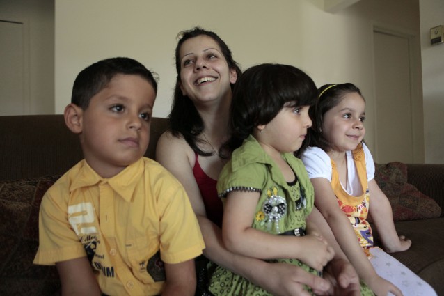 In this Friday, Aug. 21, 2009 photo, Iraqi refugee Rawaa Bahoo smiles with her children Marvin 8, left, Maryana, 4, center, and Maryam, 5, in Farmington Hills, Mich. Tens of thousands have fled Michigan’s troubled economy in recent years, yet Iraqi refugees continue to move there despite a U.S. government policy trying to limit refugee resettlement in the Detroit area. Family ties and cultural support from the region’s large Middle Eastern community appear no match for the U.S. effort, which tries to place refugees in cities where they stand a better chance of financial success. (AP Photo/Paul Sancya) CREDIT: AP Photo/Paul Sancya