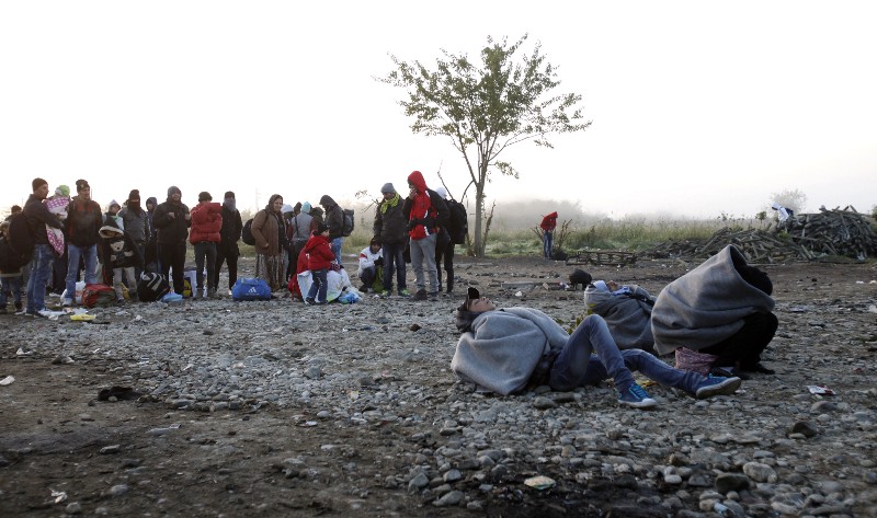 Migrants and refugees, some sleeping on the ground, wait to enter the transit center for refugees near the southern Macedonian town of Gevgelija, after crossing the border from Greece, early Friday, Oct. 30, 2015. CREDIT: AP PHOTO/BORIS GRDANOSKI