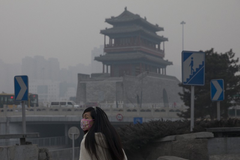 A woman wears a mask as she walks under smog in Beijing, China, Saturday, Feb. 15, 2014. CREDIT: AP PHOTO/ALEXANDER F. YUAN