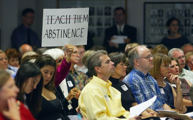 A woman in the audience holds a sign during a meeting of the State Board of Education, Wednesday, Sept. 8, 2004, in Austin, Texas. CREDIT: HARRY CABLUCK