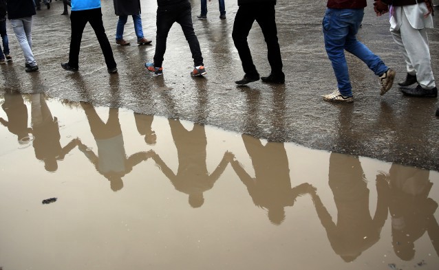 Protesters are reflected in a puddle as thousands march through the Afghan capital of Kabul on Wednesday, Nov. 11, 2015, carrying the coffins of seven ethnic Hazaras who were allegedly killed by the Taliban and calling for a new government that can ensure security in the country. CREDIT: AP Photos/Massoud Hossaini