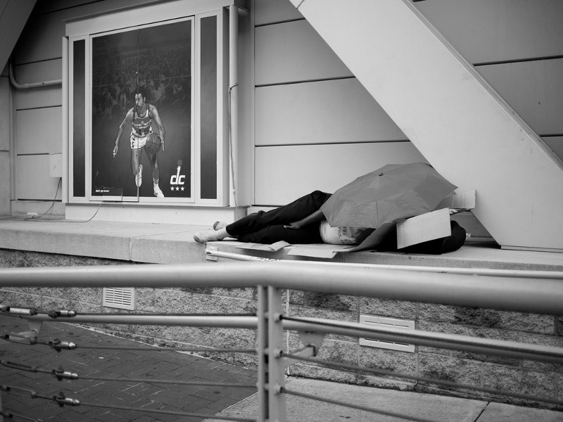 A homeless person sleeps near the downtown Washington, D.C. arena where three of the city’s professional sports teams play. CREDIT: FLICKR/DEVIN SMITH