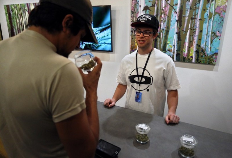 An employee helps a customer smelling the scent of marijuana for sale on opening day of a new outlet of the Colorado Harvest Company recreational marijuana stores in Aurora, Colo., Wednesday, Sept. 16, 2015. CREDIT: AP Photo/Brennan Linsley