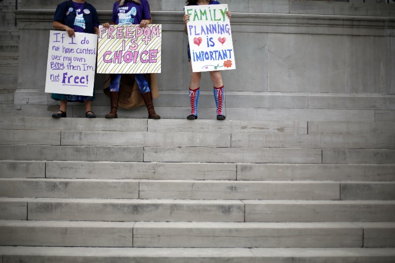Abortion rights activists hold signs as they stand on the steps of the Missouri Capitol CREDIT: AP PHOTO/JEFF ROBERSON