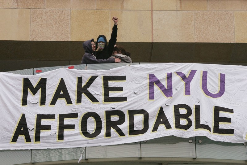 A student raises his fist as he and others are seen bracing against the cold on a balcony above a banner in the Helen and Martin Kimmel Center for University Life on the New York University campus in New York, Friday, Feb. 20, 2009. About 60 students staged a protest at NYU by talking over the Center on Wednesday evening, Feb. 18. Of those protesters, about two dozen remained on Friday morning. (AP Photo/Robert Mecea) CREDIT: ROBERT MECEA, AP