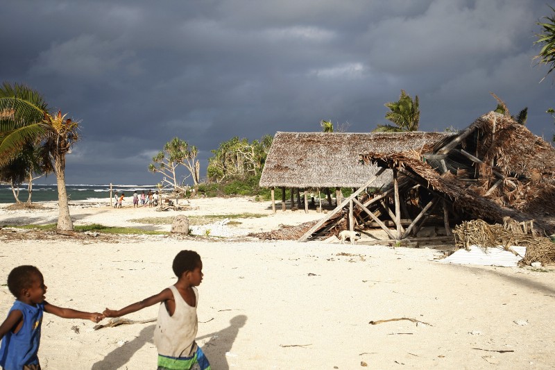 In this Saturday, May 30, 2015, photo, children play on the beach in the town of Takara, on Efate Island, Vanuatu. The town was damaged in March during Cyclone Pam. Many people in the town are considering rebuilding their community on higher ground to escape what they believe are the ongoing effects of climate change. CREDIT: AP PHOTO/NICK PERRY
