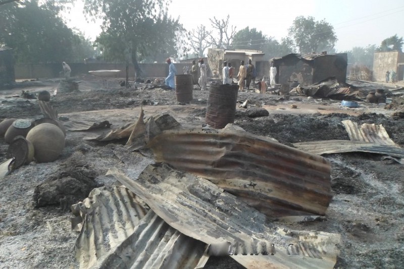 People walk past burnt out houses following an attack by Boko haram in Dalori village, Nigeria on Sunday Jan. 31, 2016. CREDIT: AP Photo/Jossy Ola