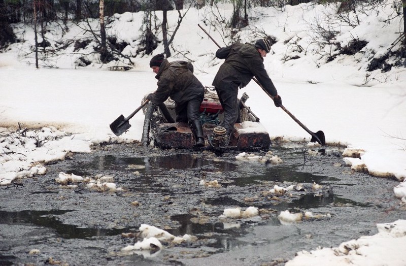 Two Russian oil workers use a boat and shovels to gather oil and mud from the waters of a small river, a tributary of the Kolva River, some 37 miles north of Usinsk, an Arctic town six miles from the Arctic Circle in Russia, Friday, Oct. 28, 1994. CREDIT: (AP Photo/Alexander Zemlianichenko)