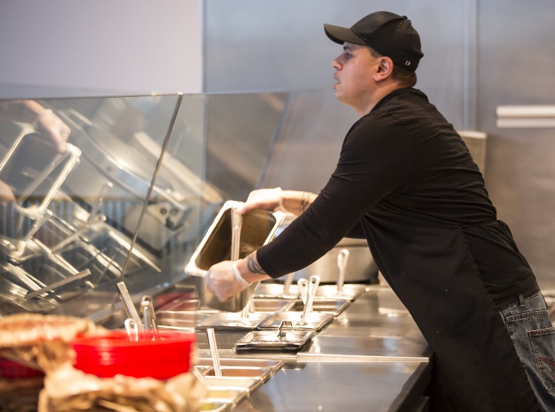 A Chipotle Mexican Grill employee prepares food in Seattle. CREDIT: AP PHOTO/STEPHEN BRASHEAR
