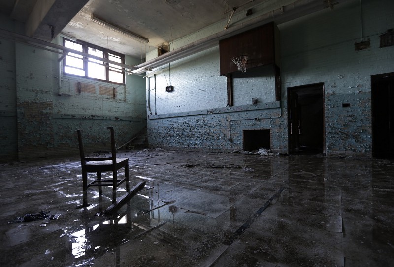 In a photo from May 16, 2013 at Crosman School in Detroit, water pools on the warped tile of what was once a basketball court. No one knows how long the water has flowed through the moldy bowels of the massive building a few miles north of downtown, but Crosman has been closed since 2007. Its not the only empty structure where city water steadily fills dark basements or runs into the gutter, wasting money and creating safety hazards. CREDIT: CARLOS OSORIO, AP