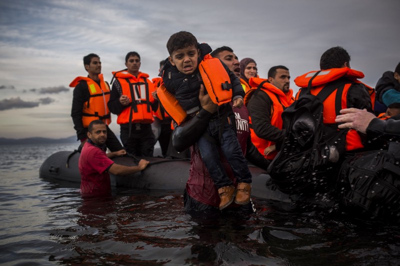Volunteers assist refugees from a dinghy after they crossed a part of the Aegean sea from Turkey to the northeastern Greek island of Lesbos, on Tuesday, Nov. 24, 2015. CREDIT: AP PHOTO/SANTI PALACIOS
