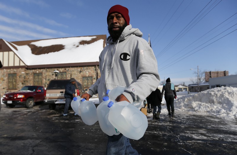 Lemott Thomas carries free water being distributed at the Lincoln Park United Methodist Church in Flint, Mich., Tuesday, Feb. 3, 2015 CREDIT: AP PHOTO/PAUL SANCYA