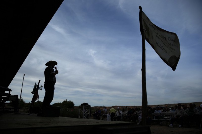 Ammon Bundy speaks at a rally on the anniversary of Cliven Bundy’s stand against the federal government. The flag that waves beside him is the “Title of Liberty,” a Mormon flag. CREDIT: AP Photo/John Locher