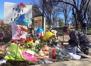An unidentified woman kneels near a makeshift memorial for Kayla Mueller in Prescott, Ariz. on Feb. 15, 2014. CREDIT: AP Photo/Brian Skoloff, File)