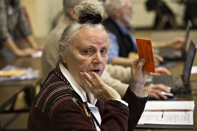 In Fairfax County, Virginia, an election officer who checks voter identification waits for a supervisor to clarify an ID problem, at the Washington Mill Elementary School near Mount Vernon, Tuesday, Nov. 6, 2012. CREDIT: AP PHOTO/J. SCOTT APPLEWHITE