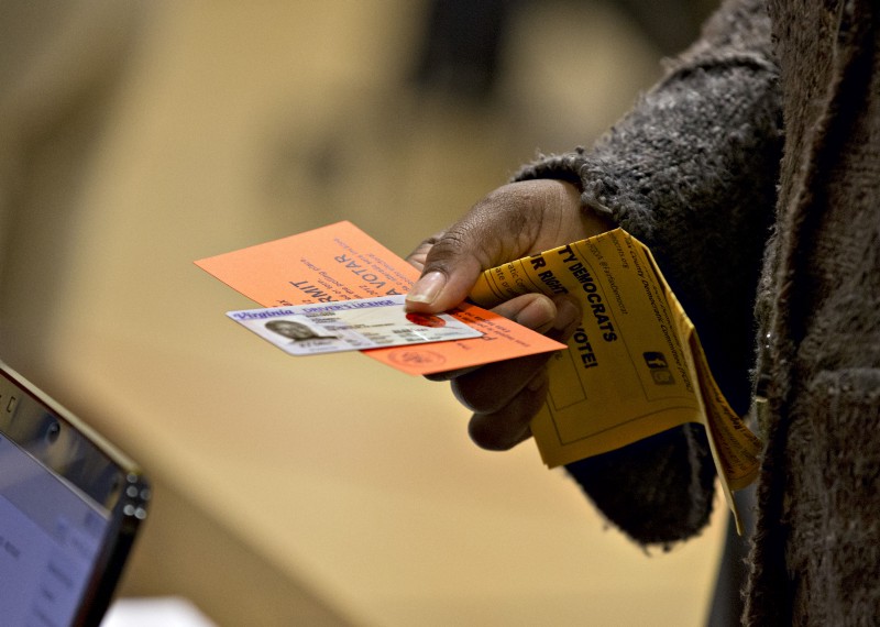 In this Nov. 6, 2012 file photo, a voter holds their voting permit and ID card at the Washington Mill Elementary School near Mount Vernon, Va. Across the South, Republicans are working to take advantage of a new political landscape after a divided U.S. Supreme Court freed all or part of 15 states, many of them in the old Confederacy, from having to ask Washington’s permission before changing election procedures in jurisdictions with histories of discrimination. CREDIT: AP PHOTO/J. SCOTT APPLEWHITE,