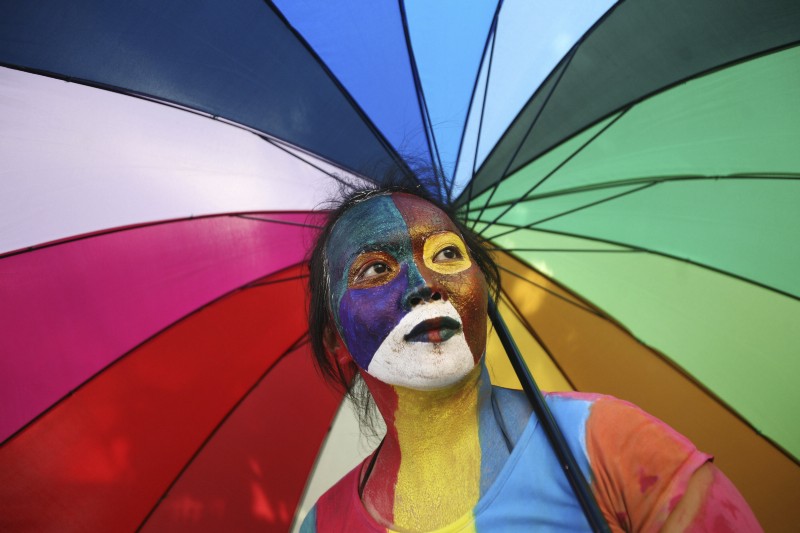 An activist with multicolored paint on her face and matching umbrella particiaptes a protest demanding equality for LGBT people in Medan, North Sumatra, Indonesia on Friday, May 31, 2012. CREDIT: AP PHOTO/BINSAR BAKKARA