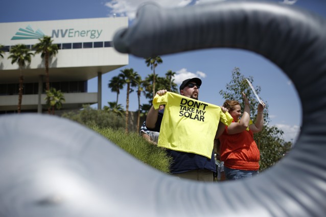 Michelle Balistreri, right, and Chandler Gray attend a rally in front of NV Energy, Wednesday, April 22, 2015, in Las Vegas. Hundreds of activists gathered outside NV Energy headquarters in Las Vegas to protest a state cap affecting rooftop solar installations and urge the Legislature to lift it. CREDIT: AP Photo/John Locher