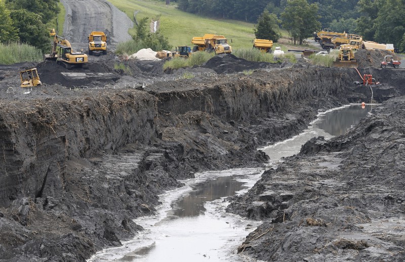 Trucks haul coal ash from one retention pond to a permanent pond at the Dominion Power’s Possum Point Power Station in Dumfries, Va., Friday, June 26, 2015. CREDIT: AP PHOTO/STEVE HELBER