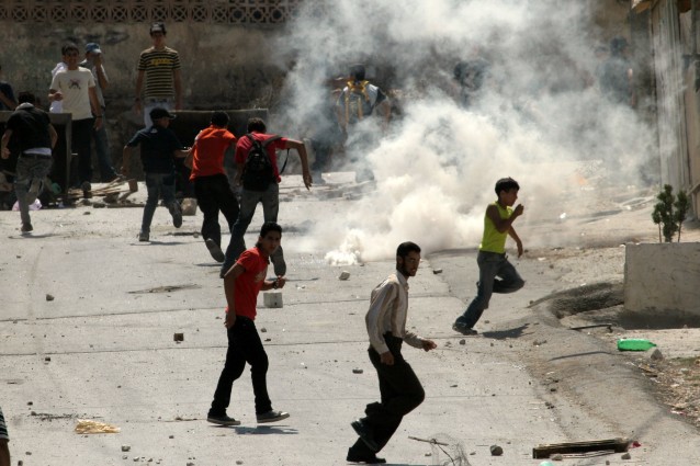 Palestinians run for cover from tear gas fired by Israeli soldiers. CREDIT: AP Photo/Nasser Ishtayeh