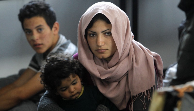 A Syrian woman holds a baby, sitting in a tent at the transit center for refugees near northern Macedonian village of Tabanovce.