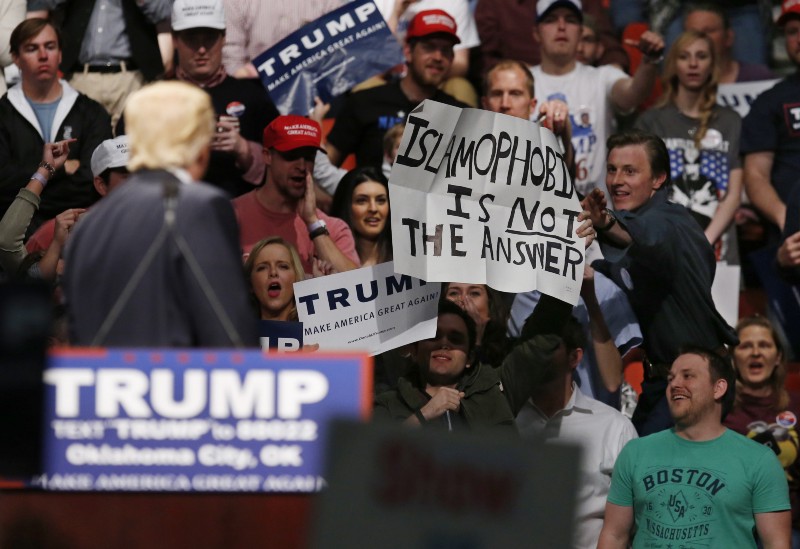 Donald Trump looks on as a supporter reaches for a sign that reads “Islamophobia is not the answer” at a rally in Oklahoma City, Friday, Feb. 26, 2016. CREDIT: AP PHOTO/SUE OGROCKI