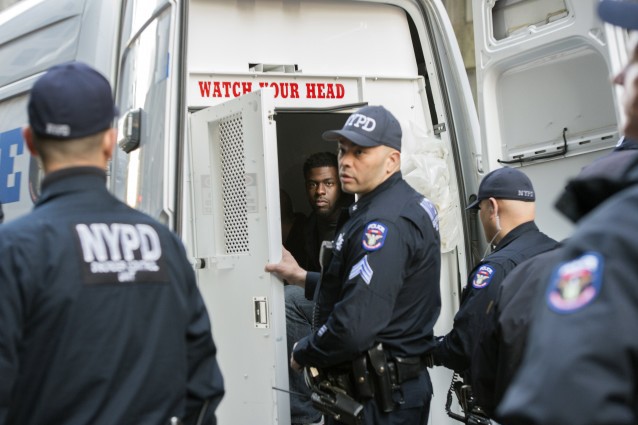 A protester sits in the back of a police van following his arrest at the Grand Hyatt Hotel.