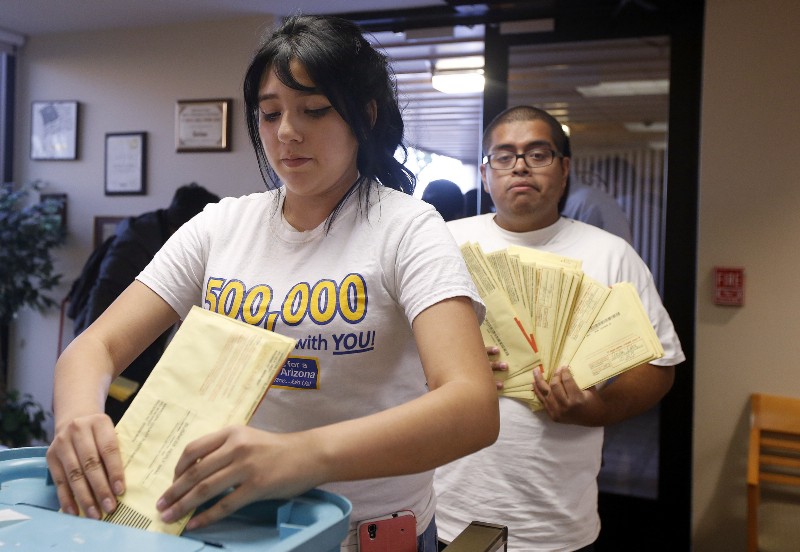Sonya Valdez, left, a volunteer for Citizens For A Better Arizona, joins about a dozen others as they place nearly 300 ballots in a voting ballot box at the Maricopa County Recorder/Elections Office Tuesday, Nov. 4, 2014, in Phoenix. CREDIT: AP PHOTO/ROSS D. FRANKLIN