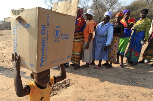 A young boy carries a box with items distributed by the United Nations World Food Program (WFP) in Zimbabwe. CREDIT: AP Photo/Tsvangirayi Mukwazhi