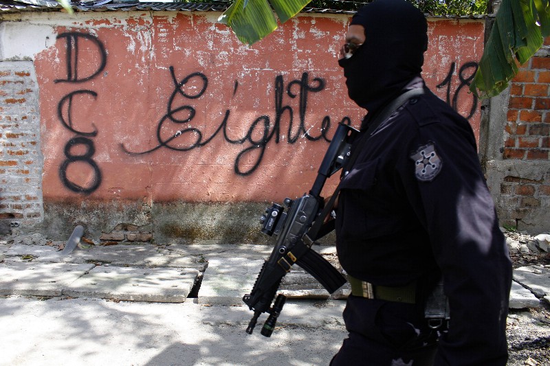 A masked and armed policeman patrols a gang controlled neighborhood in San Salvador, El Salvador on April 5, 2016. CREDIT: AP PHOTO/ALEX PEÑA)