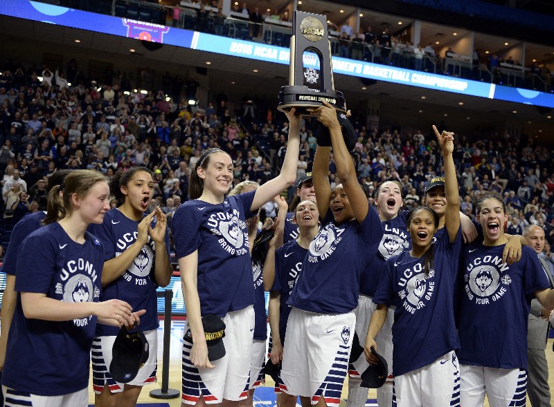 Connecticut’s Breanna Stewart, left, and Morgan Tuck celebrate with the trophy and teammates after winning 86–65 over Texas in a college basketball game in the regional final of the women’s NCAA Tournament, Monday, March 28, 2016, in Bridgeport, Conn. CREDIT: JESSICA HILL, AP