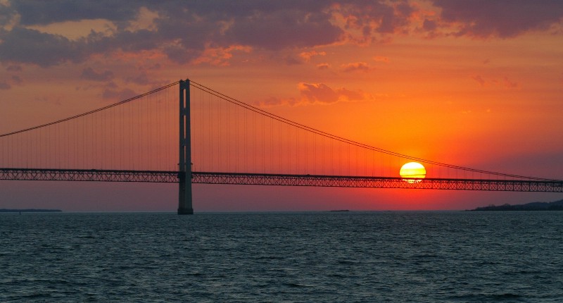 The sun sets over the Mackinac Bridge and the Mackinac Straits as seen from Lake Huron. A 62-year-old oil and gas pipeline runs underneath and is now under the spotlight as its considered too risky to keep. CREDIT: AP PHOTO/AL GOLDIS
