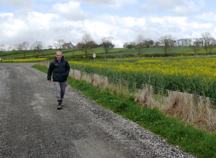 Friends of the Earth campaigner Simon Bowen walks along the dirt road leading to the fracking site, located in the copse of trees to the right of the farmhouse in the background. CREDIT: Samantha Page/ThinkProgress